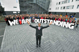 Walsall students standing behind a sign saying 'We are outstanding'.