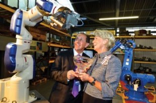 Ingrid Roscoe and Mark Ridgway standing beside a robotic arm.