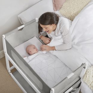 Mum comforting baby in a bedside crib.
